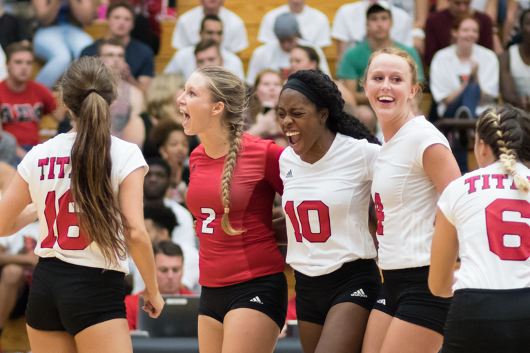 Photo of the IU South Bend Women's Volleyball team smiling and laughing on the court together.